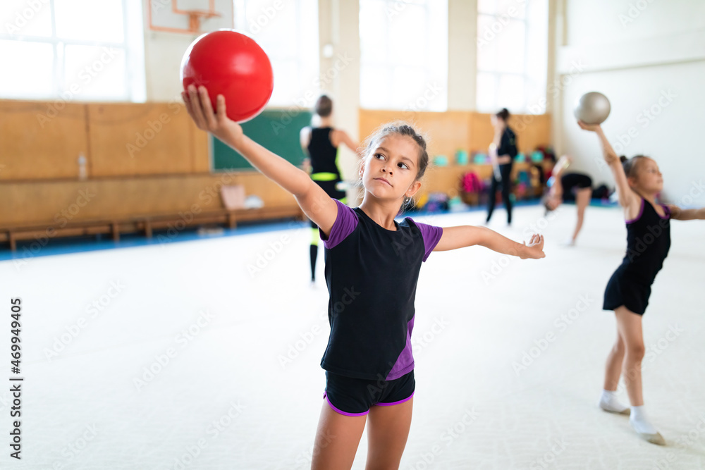 Ταπετσαρία Girl gymnast doing exercise with ball on training in gym with other girls