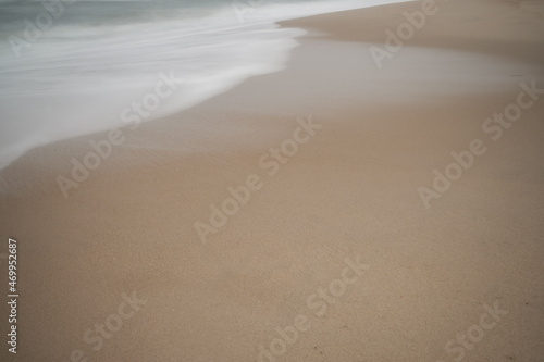 Soft focus beach foam rolls onto an empty beach during an Atlantic storm