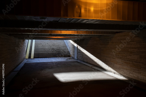 Old underground pedestrian tunnel, crossing the city street highway. Dim tunnel poorly lit by a lamp.