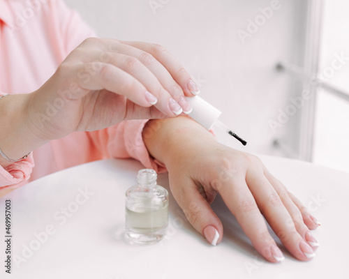 Woman used oil to hydrate her skin.   Woman s hand dripping oil. Moisturizing oil is dropping on hand s skin from pipette.