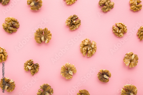 Brown walnuts on light pink table background. Pastel color. Closeup. Food pattern. Top down view.