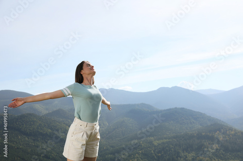 Beautiful young woman in peaceful mountains on sunny day. Feeling freedom