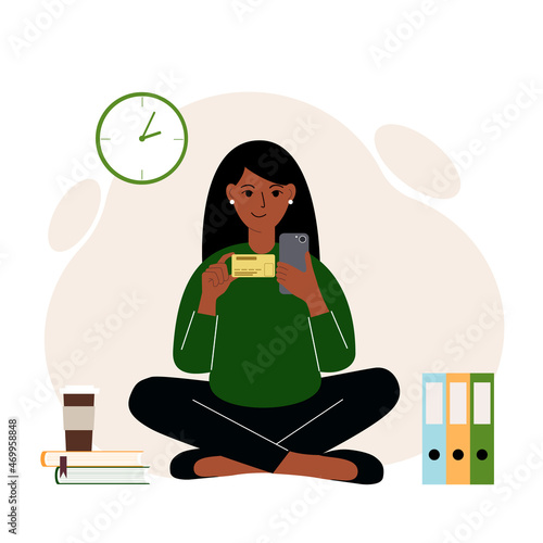 A woman sits cross-legged with a mobile phone in one hand and a bank card in the other. Concept of online credit