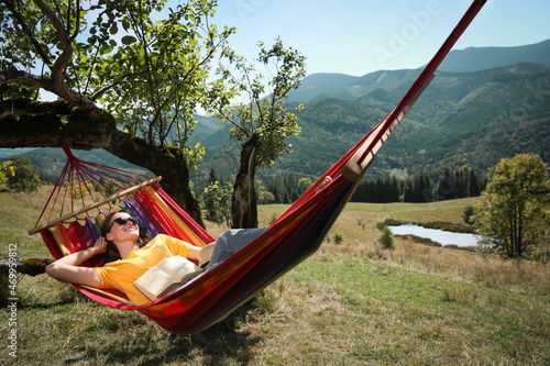 Young woman resting in hammock outdoors on sunny day