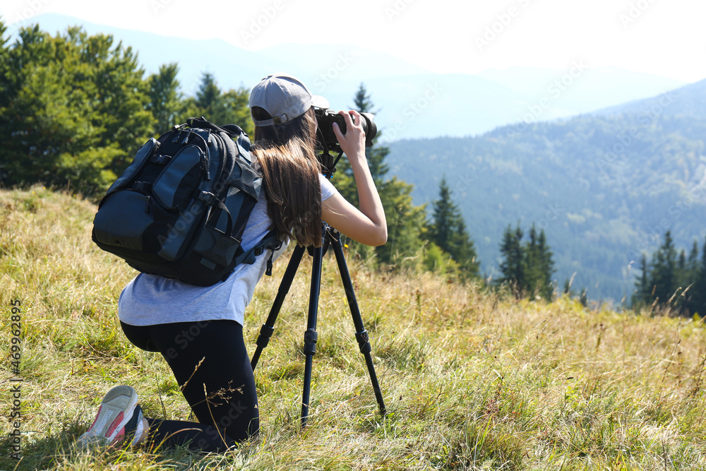 Woman taking photo of mountain landscape with modern camera on tripod outdoors