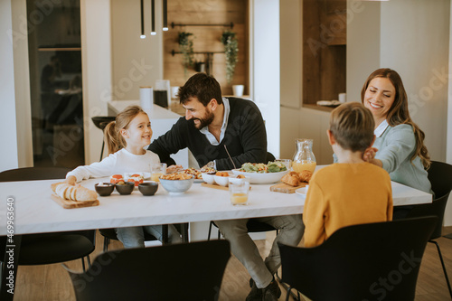 Young happy family talking while having lunch at dining table