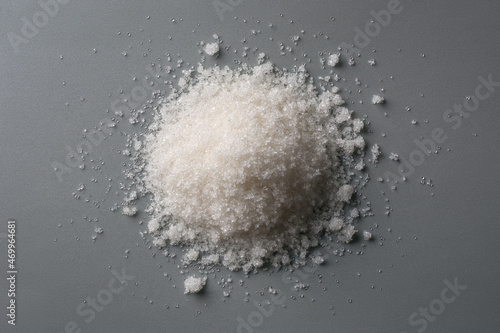 pile of granulated white sugar, also called table sugar, on a neutral gray background, top view, flat lay