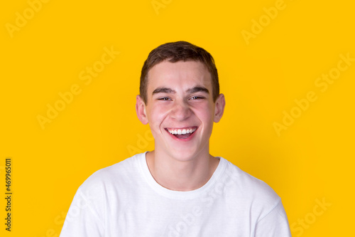 A handsome guy in a white t-shirt gesticulating on a yellow background