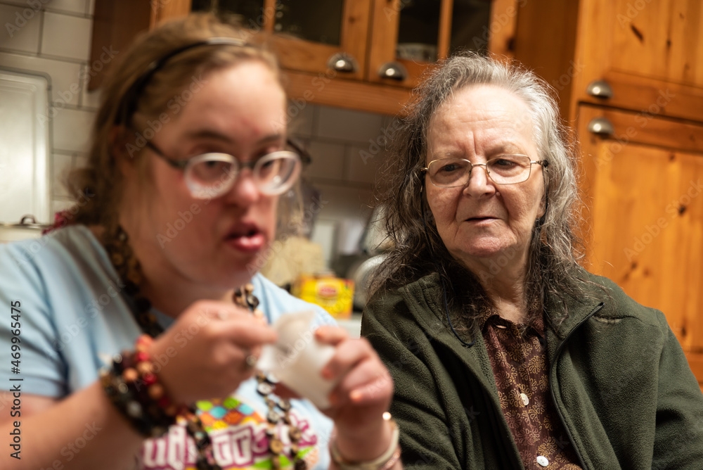 Hakendover, Flemish Brabant, Belgium - 09 20 2021: Disabled 39 year old woman and her 83 year old mother having fun in the kitchen at home