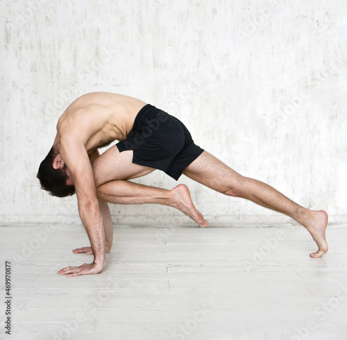 A young man is doing yoga. Yoga coach on a light background.