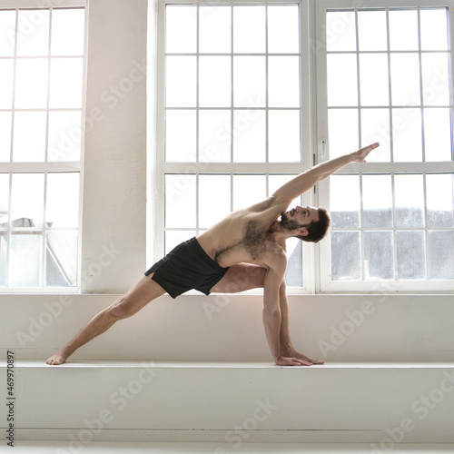 Fototapeta Naklejka Na Ścianę i Meble -  A young man is doing yoga. Yoga coach on a light background.