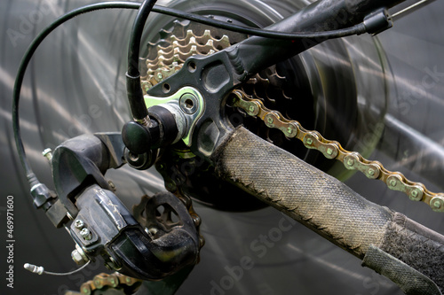 Bicycle repair in the workshop. Photo of the rear wheel during rotation with the effect of movement. Installing an electric motor on a bicycle. Rear derailleur and rusty chain close-up