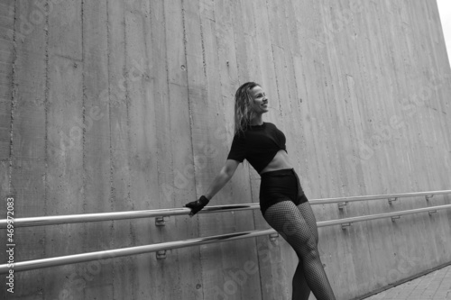 Black and white shot of blonde attractive woman in a dance pose over wall.