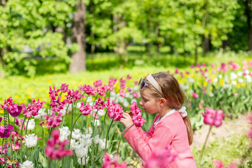 portrait of a very cute pretty girls blonde in a pink coat around the flower bed of tulips in the Park.Beautiful child smelling flowers on tulip fields. Child in tulip flower field portrait of a very cute pretty girls blonde in a pink coat around the flower bed of tulips in the Park.Beautiful child smelling flowers on tulip fields. Child in tulip flower field