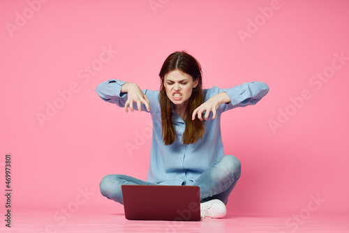 woman sitting on floor with laptop shopping entertainment pink background