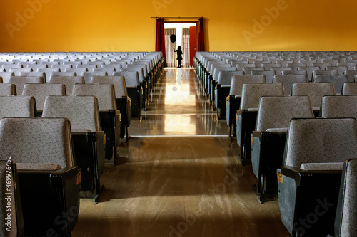 aisle with armchairs at the sides and at the back a door with a silhouette of a girl with a balloon.