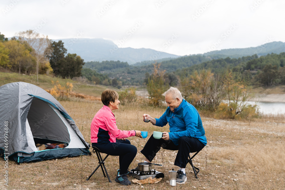 Senior couple eating and camping after trekking day at the lake - Focus on woman face Senior couple eating and camping after trekking day at the lake - Focus on woman face