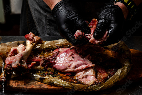 the cook is cutting smoked meat. smoked leg of beef