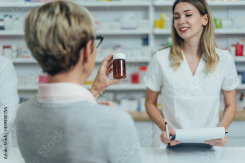 Pharmacist giving prescription medications to smiling senior female customer