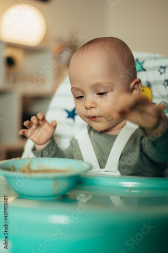 Adorable little baby eating his dinner and making a mess