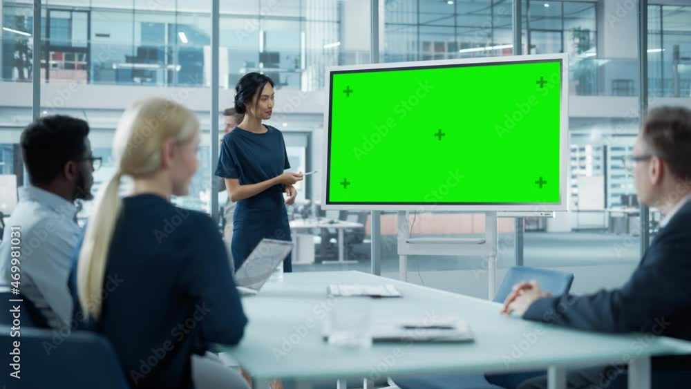 Female Operations Manager Holds Meeting Presentation for a Team of Economists. Asian Woman Uses Digital Whiteboard with Horizontal Green Screen Mock Up Display. People Work in Business Office.