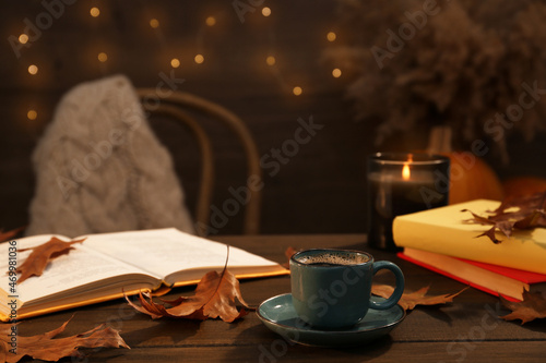 Cup of aromatic coffee, books and autumn leaves on wooden table indoors. Space for text