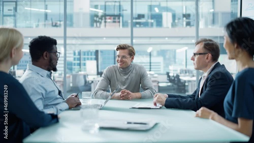 Wallpaper Mural Modern Office Meeting Room: Handsome Executive Director Sits in the Head of the Conference Table and Delivers Strong Speech to a Group of Businesspeople and Talks with Investors. Torontodigital.ca