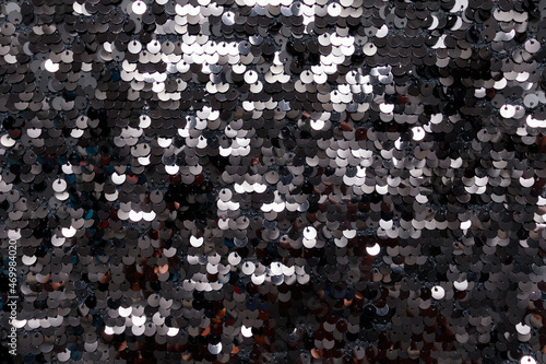 Shiny black sequins on fabric. Abstract shiny background, fashionable fabrics, blex, sequins. Fabric for festive events
