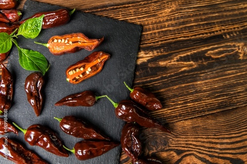 Chili pepper on wooden background.Extra hot chili. Naga Bhut Jolokia Chocolate. Exotic spices. Hot ingredients for food.