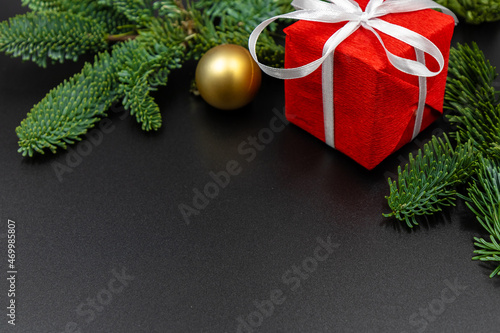 New Year's background. A spruce branch and a red gift box close-up. Black background