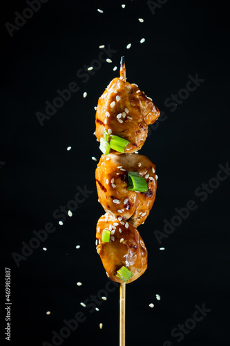Photography Skewer with chicken fillet on a black background, yakitori is a classic Japanese dish