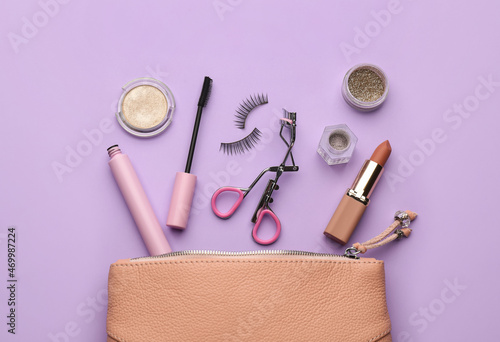 Fototapeta Naklejka Na Ścianę i Meble -  Eyelash curler, cosmetic bag and makeup products on violet background, flat lay