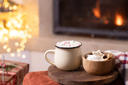Cozy home atmosphere. Christmas hot drink - a beautiful cup of cocoa, hot chocolate with marshmallows, traditional cookies by the fireplace. Winter holidays, time at home concept. Copy space. Vertical