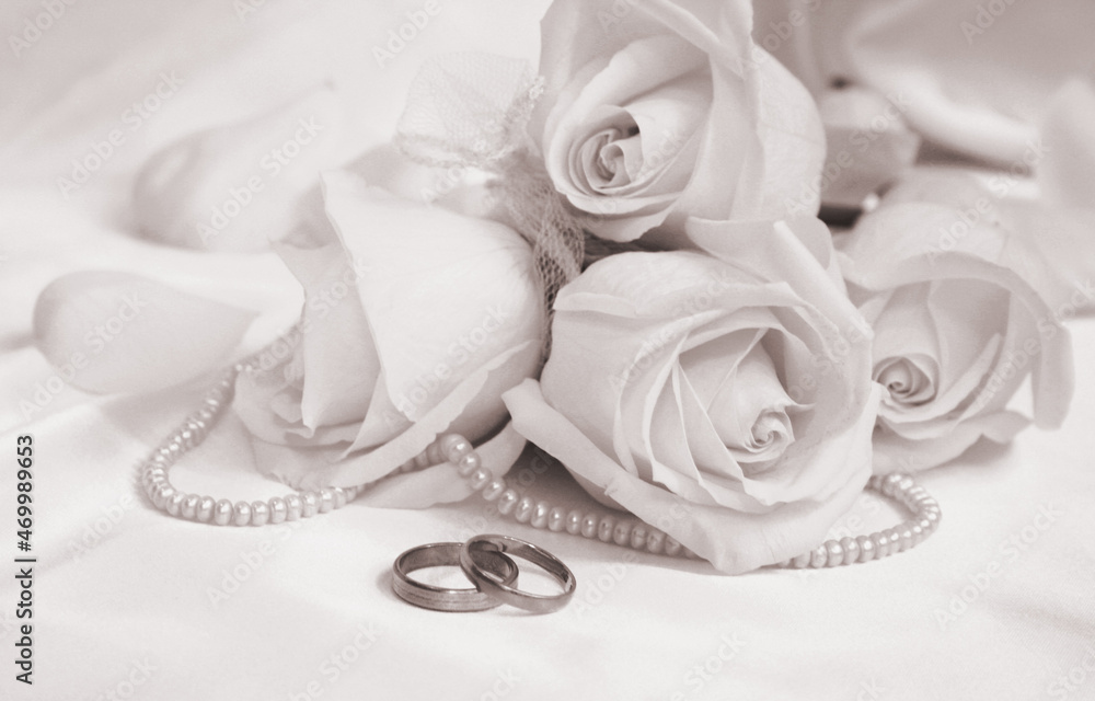 Wedding rings and roses on white silk as wedding background. Soft focus. In Sepia toned. Retro style Wedding rings and roses on white silk as wedding background. Soft focus. In Sepia toned. Retro style