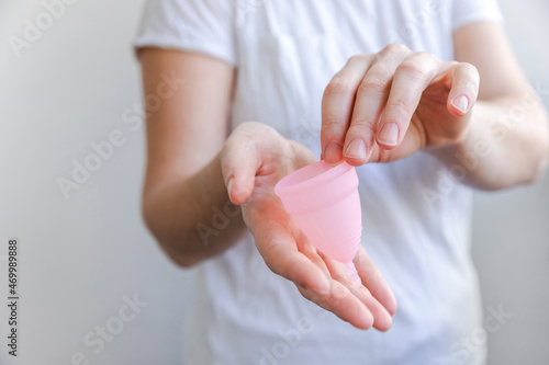 Woman hand holding pink menstrual cup isolated on white background. Woman modern alternative eco gynecological hygiene in menstruation period. Container for blood in girl hand