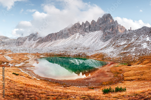 Clear turquoise water of alpine lake Piani in the Tre Cime Di Laveredo National Park, Dolomites, Italy. Picturesque landscape with snowy mountains, orange grass and small lake in autumn Dolomite Alps photo