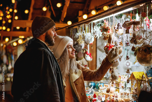 Fotografie, Tablou Christmas, winter holidays, vacation, travel, purchase conception: happy smiling couple shopping at festive street market, choosing gifts