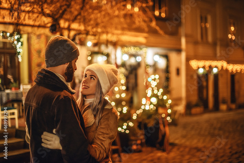 Christmas  winter holidays  vacation  New Year celebration conception  young happy hugging couple posing in street of European city. Outdoor night portrait. Copy  empty space for text 