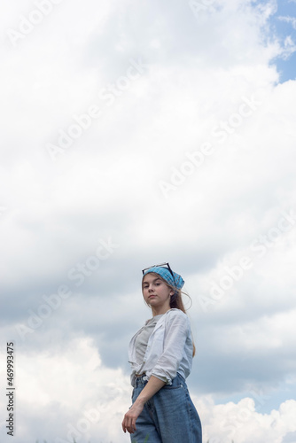 portrait of a little teenage girl in a bandana, against the backdrop of a cloudy sky © Алексей Доненко