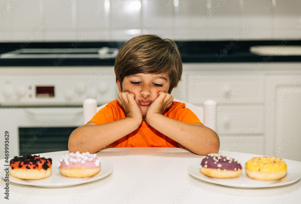 Frustrated child in front of two plates with donuts