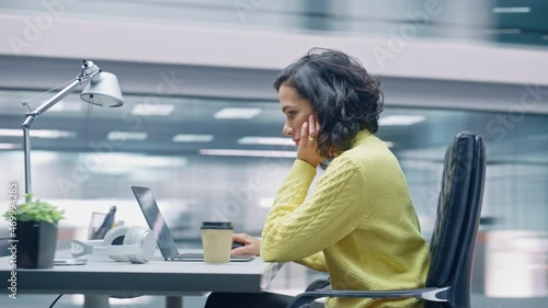 360 Degree Time-Lapse Office: Productive Latin Businesswoman Sitting at Her Desk Working on a Laptop Computer. Smiling Successful Hispanic Woman working. Energetic Moving Around Tracking Shot