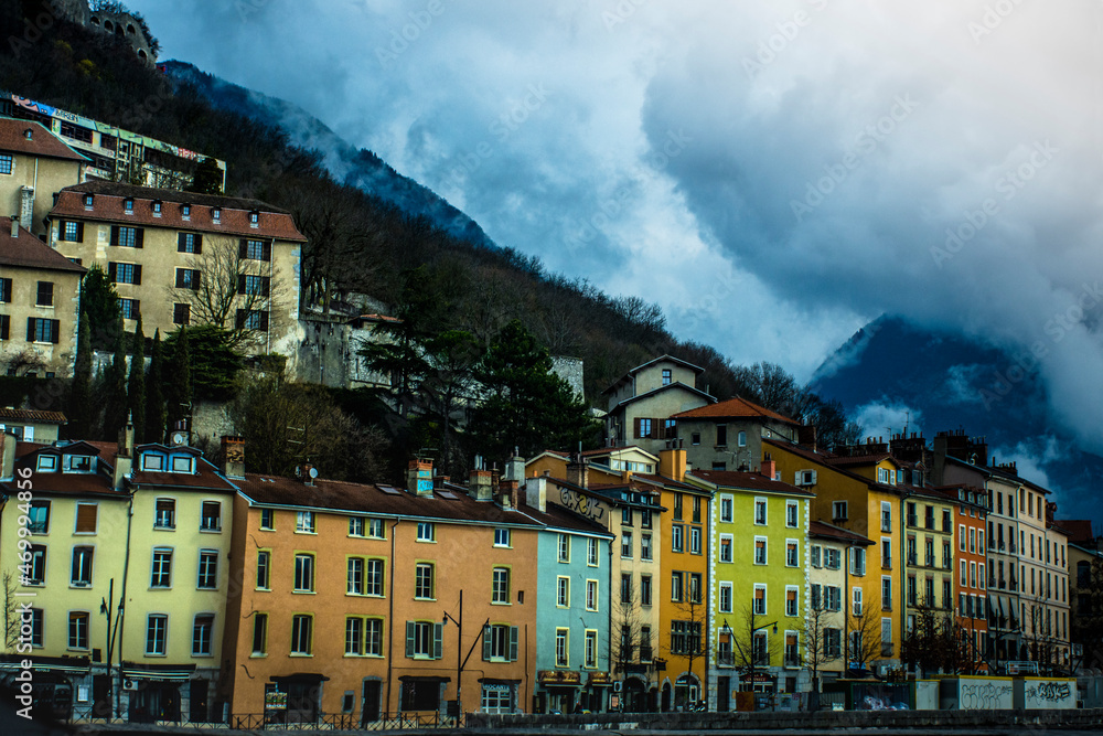 Lined buildings with different colours in a mountain in a cloudy day in Grenoble, France
