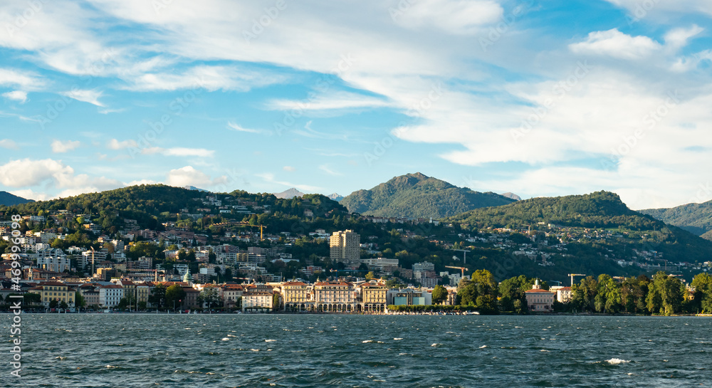 Lugano, Switzerland - October 6th 2021: Skyline of the city with surrounding mountains seen from the lake