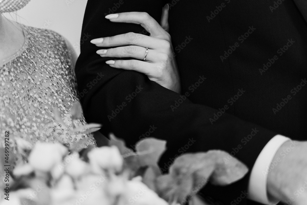 bride holding the groom's bridesmaid, close-up of the bride and groom with focus on the hands, black and white photograph of the wife's hand on the groom's shoulder
