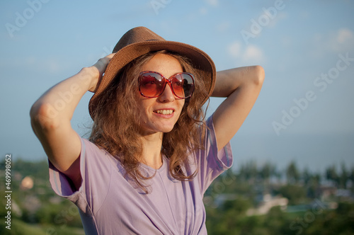 Young girl in dress is having great time during vacation in the summer on sky background in nature, travelling concept