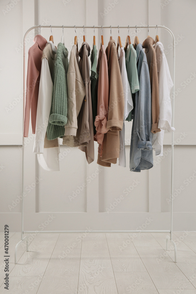 Rack with stylish women's clothes near light wall