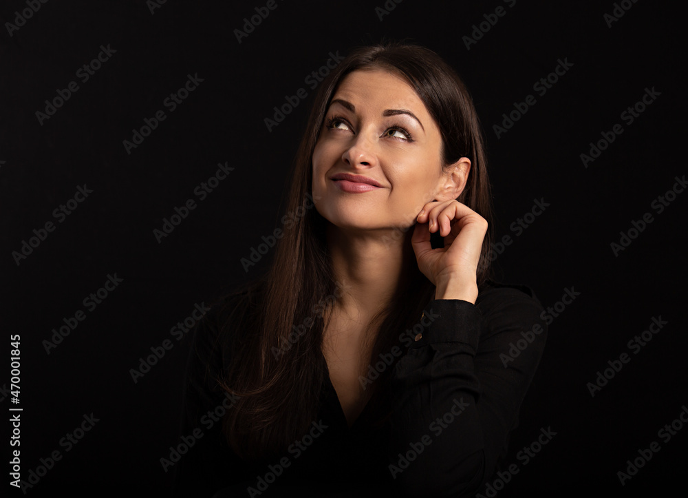 Beautiful thinking business woman looking up with hand under the face in casual black t-shirt on black background with empty copy space. Closeup Beautiful thinking business woman looking up with hand under the face in casual black t-shirt on black background with empty copy space. Closeup