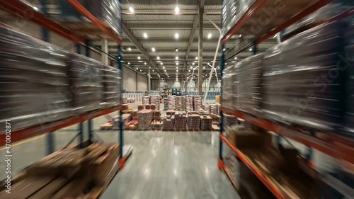 Time-lapse view inside warehouse. FPV flight between rows of shelves with delivery goods. Plenty of cardboard boxes on industrial racks. Logistic center. photo