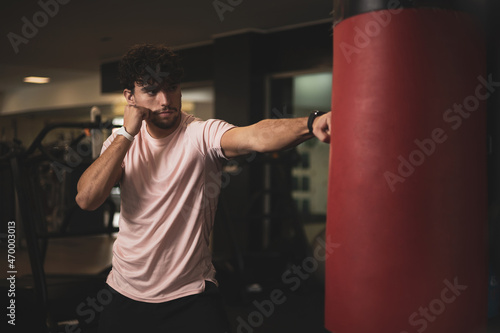 a young man hitting a punching bag in a gym.