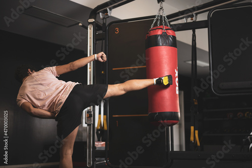 a young man hitting a punching bag in a gym.